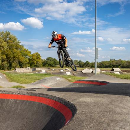 Bike rider jumping on pump track with jump lines behind