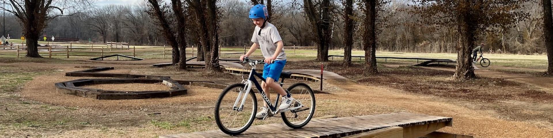 Kid riding bicycle on Teeter Totter feature in Bike Skills Course at MOmentum