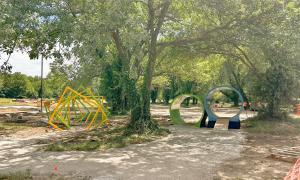 Park with geometric play structures and trees.