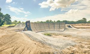 Dirt ramp at construction site under a cloudy sky.