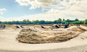 Construction site with dirt mounds under a partly cloudy sky.