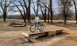 Kid riding bicycle on Teeter Totter feature in Bike Skills Course at MOmentum